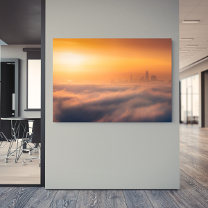 Photograph of a foggy San Francisco skyline emerging from low-lying fog during a sunrise.